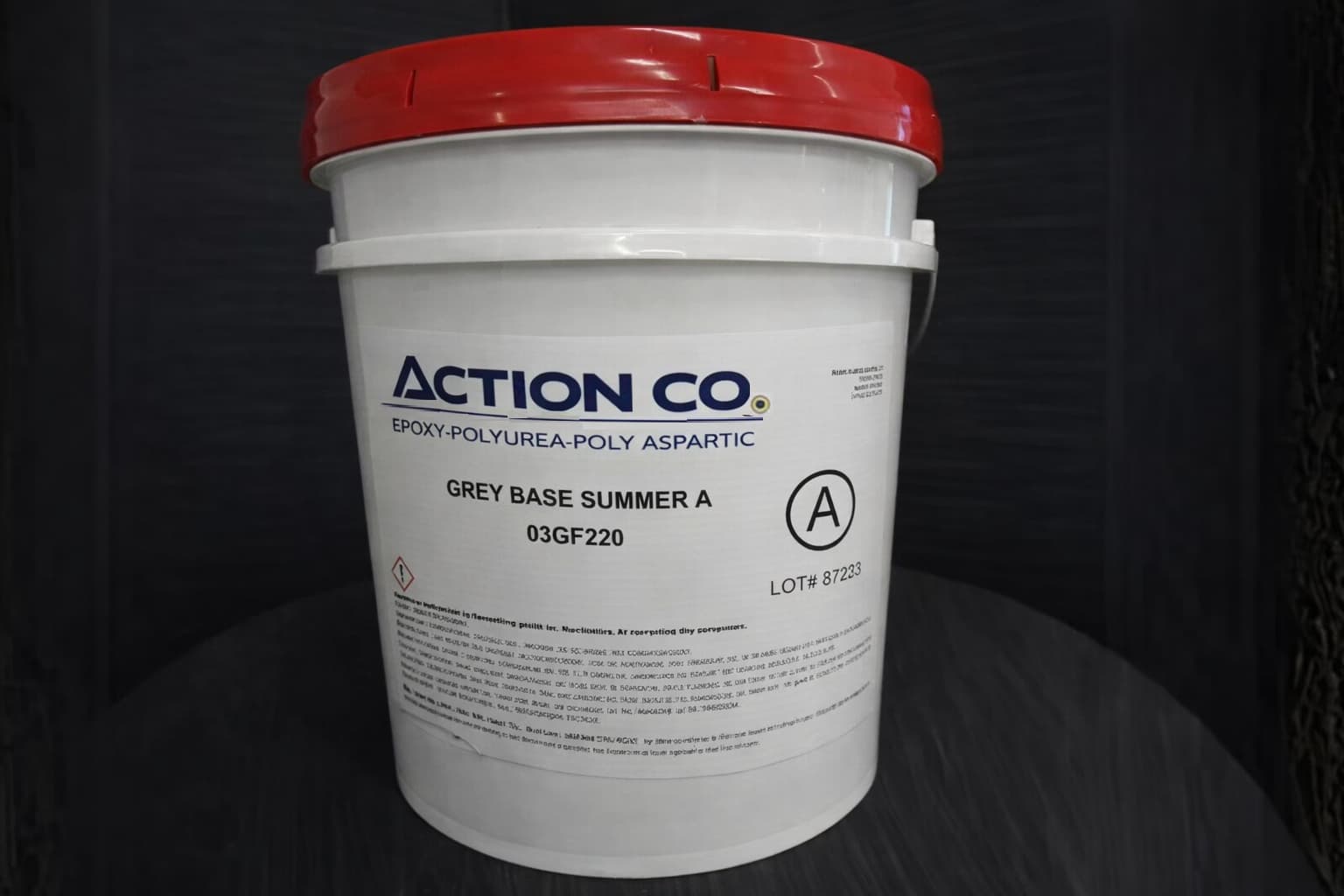 Action Co epoxy-polyurea-polyaspartic grey base coat Summer A in a 5-gallon white bucket with red lid and product label visible.